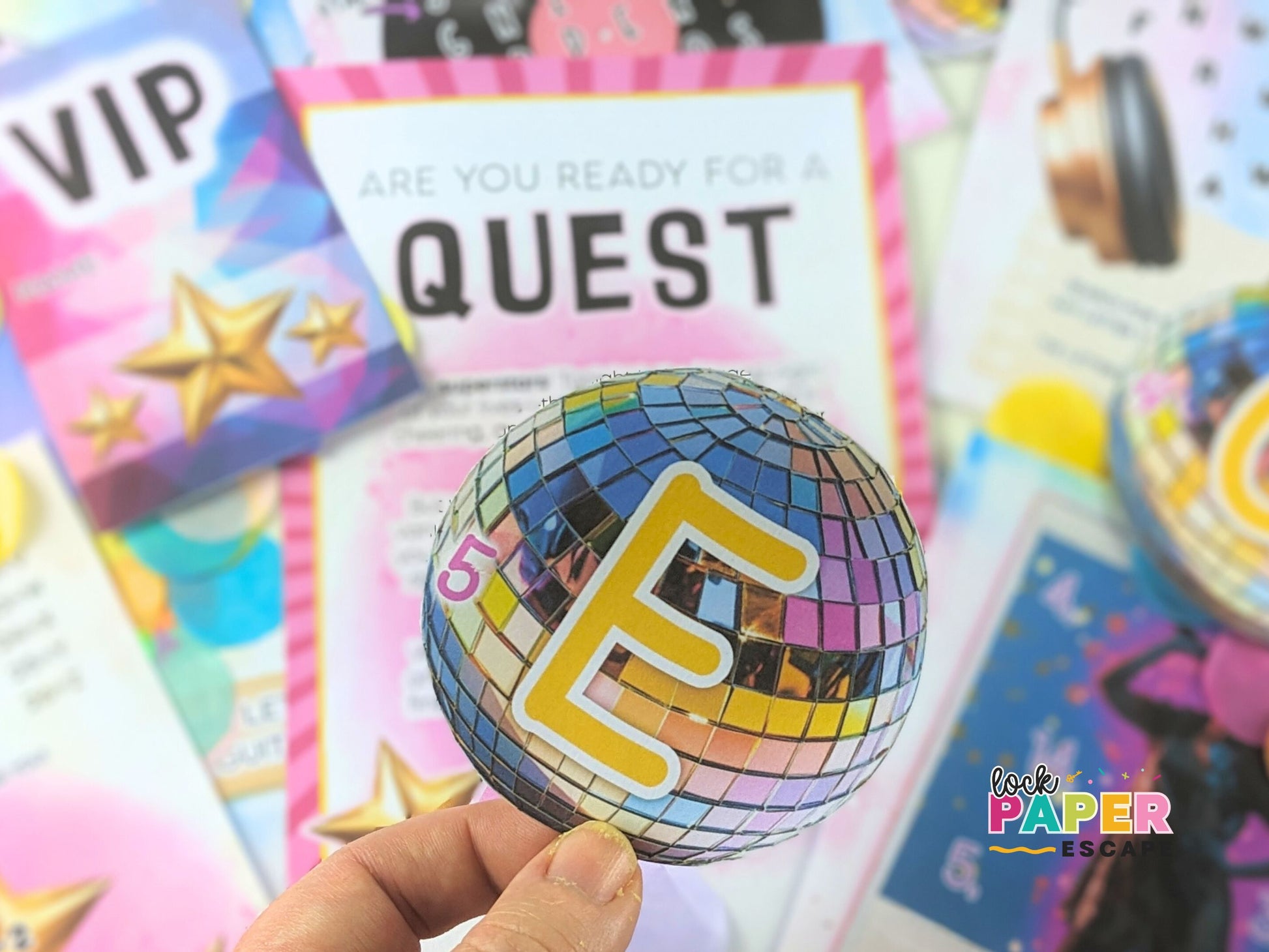 Colorful 'Quest' card with a disco ball design held by a hand, surrounded by printed escape room puzzles.