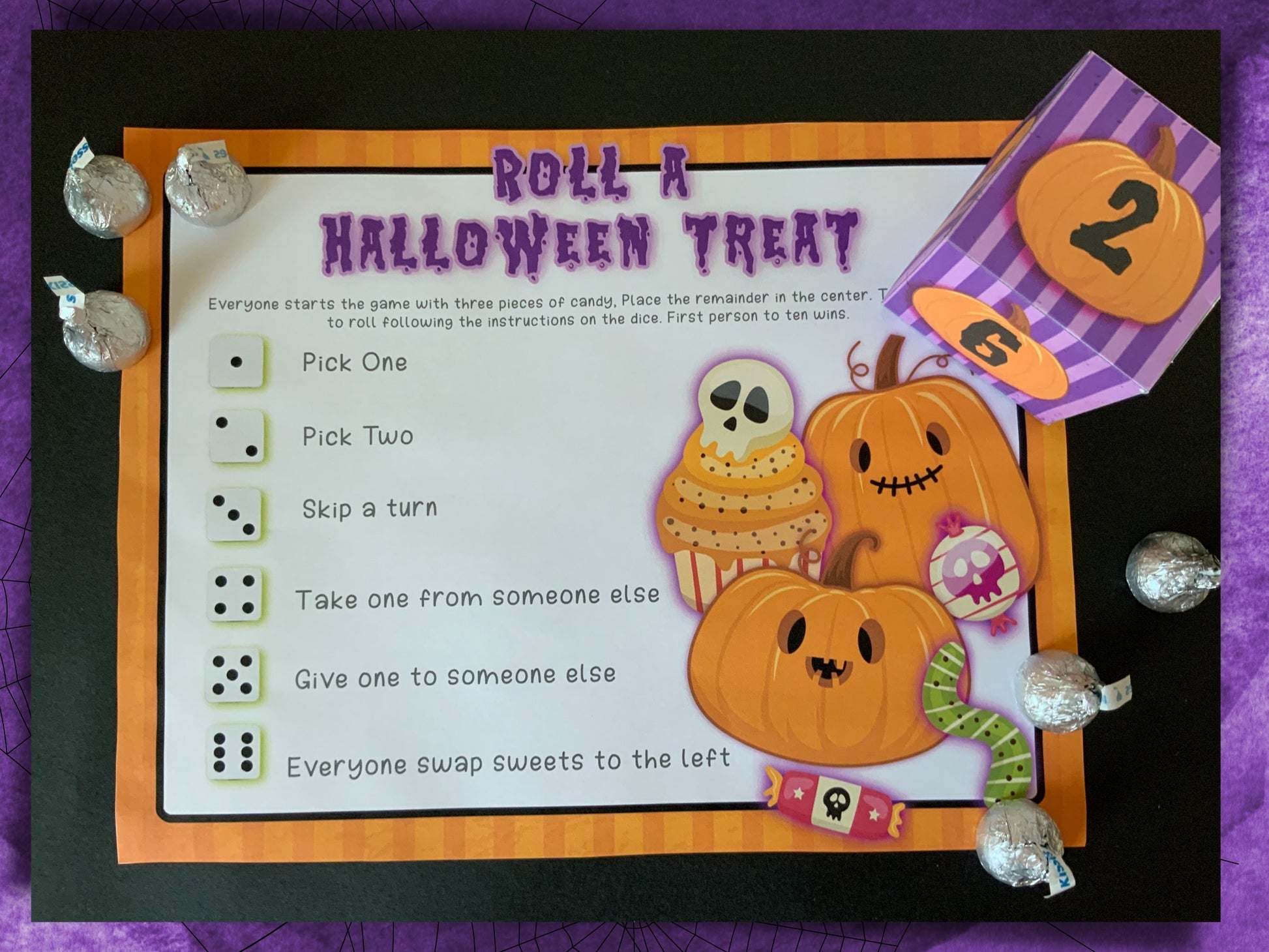 Halloween-themed candy dice game board with pumpkins and candy illustrations on a purple background.