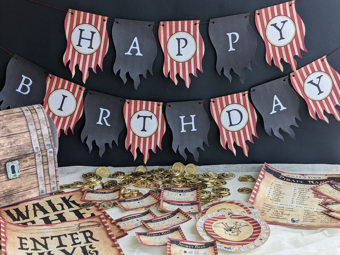 Pirate-themed birthday party decorations with 'Happy Birthday' banner, gold coins, and wooden barrel.